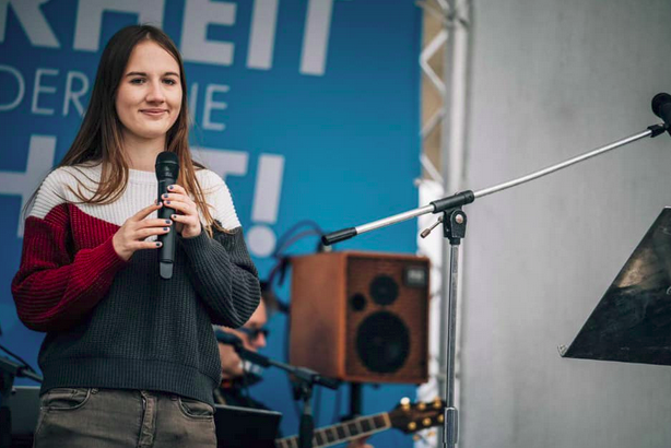 Carolin Lichtenheld steht mit Mikrofon auf einer AfD Bühne