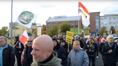 Bei der Montagsdemo in Hermsdorf sind am 3.10.2022 Menschen mit Flaggen von "Freies Thüringen" und mit abgewandelten Thüringenflaggen zu sehen. Dazwischen laufen Leute mit Schildern, die vom Volkszorn sprechen.