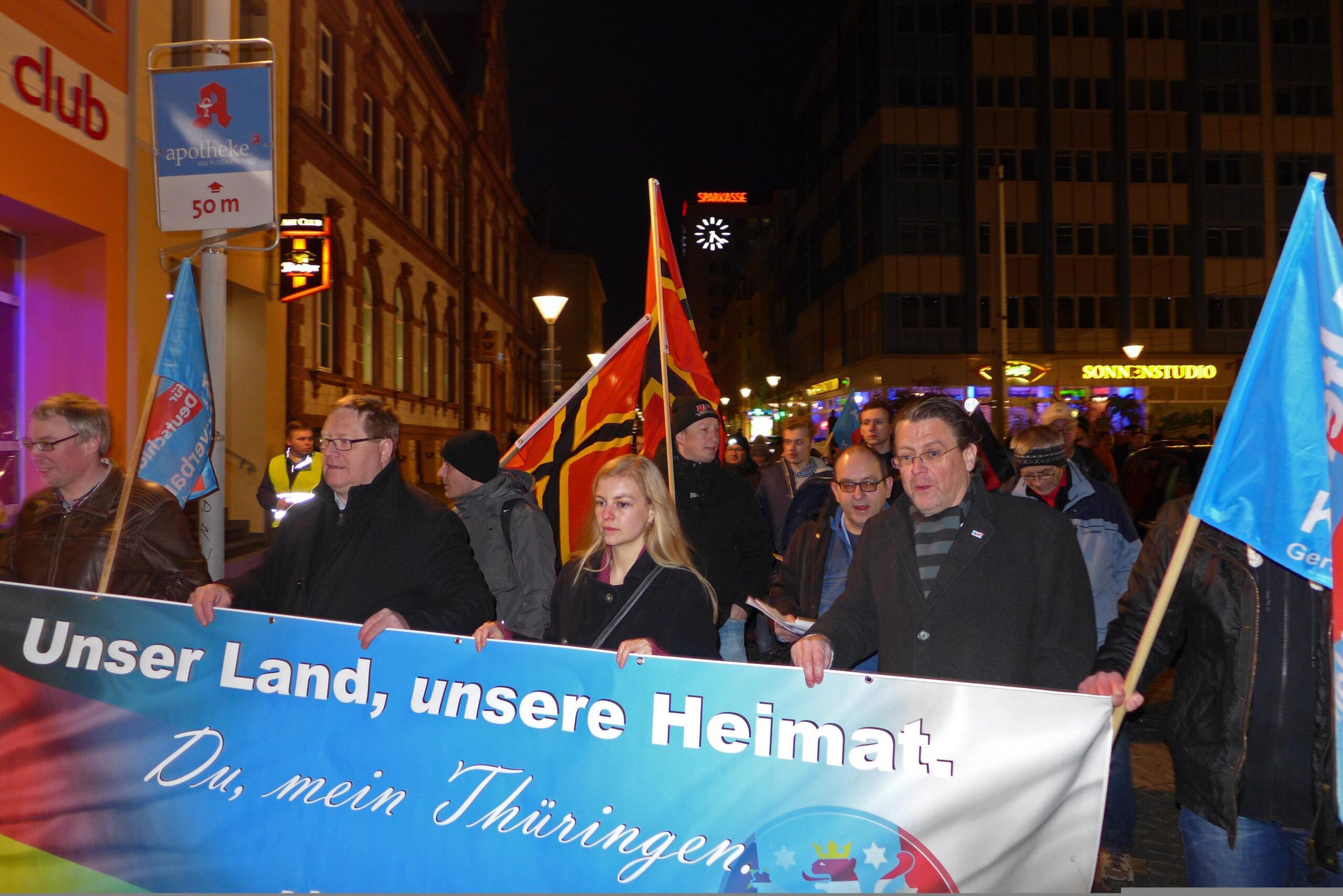 Foto der Spitze einer AfD Demonstration. Am Fronttransparent mit dem Text "Unser Land, unsere Heimat. Du mein Thüringen" laufen Denny Jankowski, Jörg Henke, Wiebke Muhsal und Stephan Brandner. Im Hintergrund laufen mehr Menschen. Zwei Personen tragen Wirmer-Fahnen.