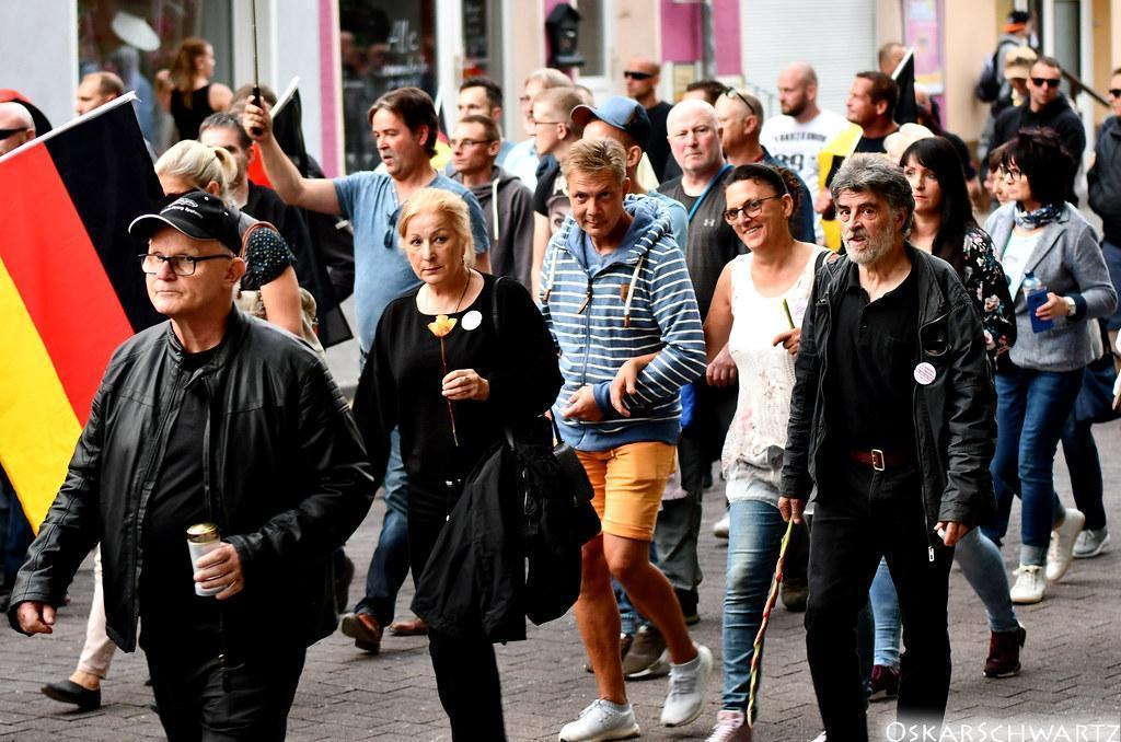 Foto einer Demonstration auf dem mehrere TeilnehmerInnen zu sehen sind. Außerdem ist eine schwarz-rot-goldene Fahne zu sehen.
