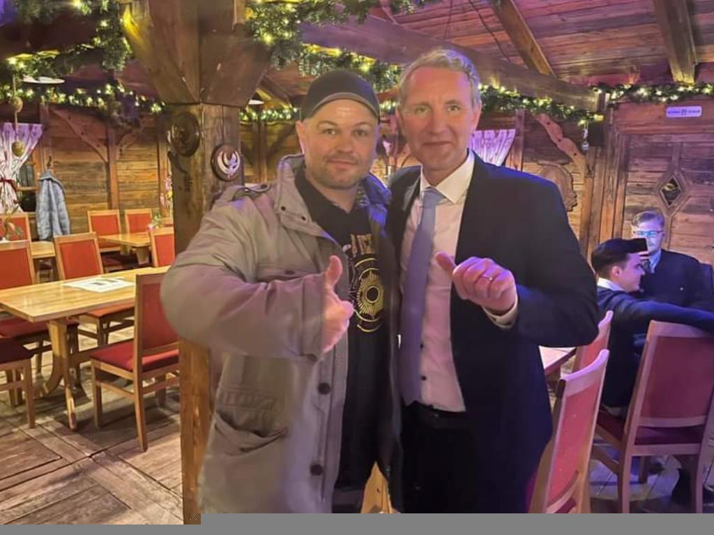 Foto von Christian Klar und Björn Höcke, die beide einen Daumen nach oben in die Kamera zeigen und eng zusammen stehen.