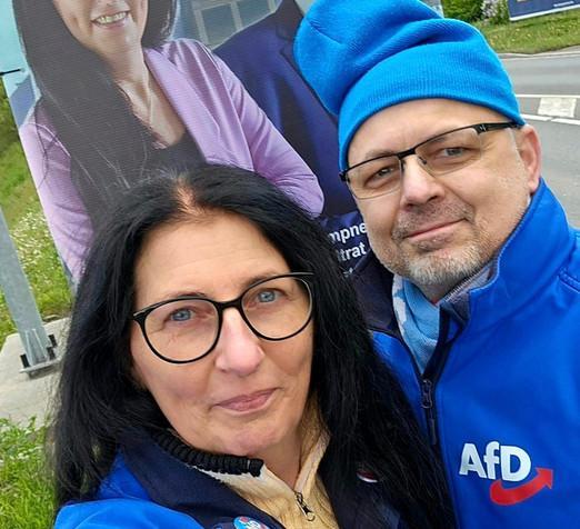 Corinna Schmit und Frank Lipfert in AfD Kleidung vor einem Wahlplakat der AfD.