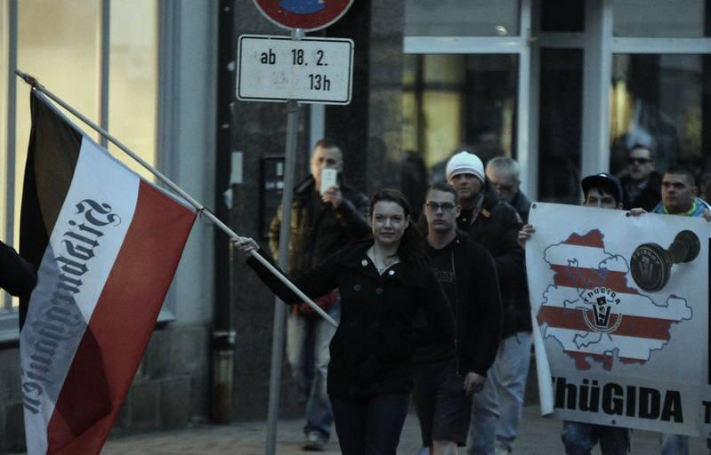 Foto eines Aufmarschs, bei dem Angela Schaller einer schwarz-weiß-rote Fahne mit der Aufschrift "Hildburghausen" trägt und vor einem Thügida-Banner läuft.