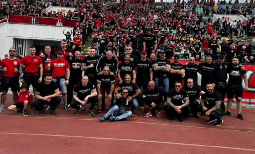 Gruppenfoto von Jungsturm-Hooligans in rot und Animals-Hooligans in schwarz im Innenraum des ZSKA-Stadions in Sofia. Im Hintergrund sieht man volle Ränge.