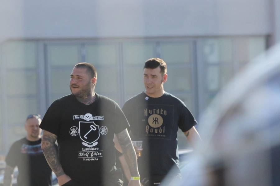 Orlin Pavlov und Michael Hein sind auf dem Parkplatz des Veranstaltungsortes bei Verona zu sehen. Pavlov trägt ein T-shirt mit einem SS-Totenkopf, dem Spruch "Meine Ehre heißt Treue" und "Leibstandarte Adolf Hitler.