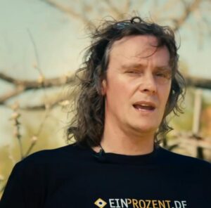 Porträtbild von Jörg Tonndorf auf dem dieser ein T-Shirt mit dem Schriftzug "EINPROZENT.DE" trägt.