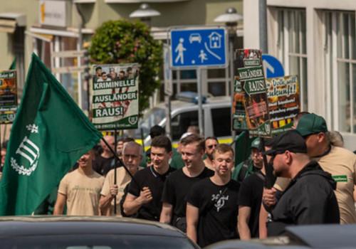 Robin Klein ist mit einem Shirt mit einem Schwert und einem Lorbeerkranz im Aufmarsch vom III. Weg am 1.5.2024 in Sonneberg zu sehen. Der Aufmarsch wird von grün und senfgeld dominiert, auf Plakaten steht „kriminelle Ausländer raus!“