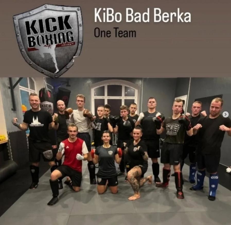Gruppenfoto nach dem Kickboxtraining beim KiBo, mit KiBo-Grafik überm Foto eingearbeitet. Ca. zwölf Personen stehen mit in Boxpose erhobenen Fäusten im Halbkreis im Ring. Auf der rechten Seite sind Neonazis zu sehen. Bildunterschrift: „Nazis im Training beim KiBo am 5.12.2024: Danilo Martin (4.v.r.), Robin Klein (3.v.r.), Kevin Pöllinger (2.v.r.), David Prinz (1.v.r.) und Heidi Lorber (unten r.)“