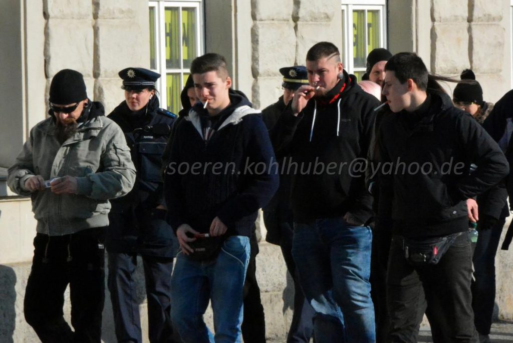 Eine Gruppe Neonazis wird vom Weimarer Bahnhof von der Polizei eskortiert. Danilo Martin läuft mit Zigarette im Mund und dunkler Kleidung in der Bildmitte