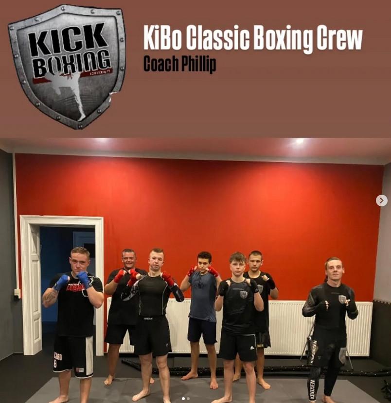 vor einer in der oberen Hälfte rot gestrichenen Wand steht eine Gruppe junger Männer in Boxpose. Darüber steht „KiBo Classic Boxing Crew“. Kevin Pöllinger steht vorne ganz links, Robin Klein vorne als 3. von links.