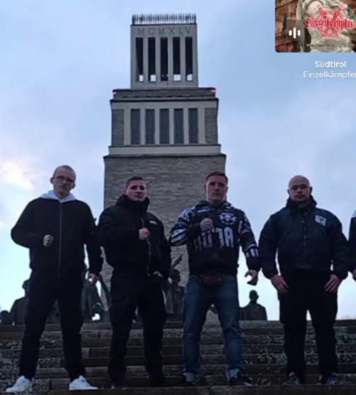 Gruppenfoto von vier jungen Männern in der Dämmerung vor dem Turm von Buchenwald. Drei Personen, darunter Kevin Pöllinger in einer Yakuza-Jacke halten die rechte Faust geballt, Ian Bütow steht rechts daneben.